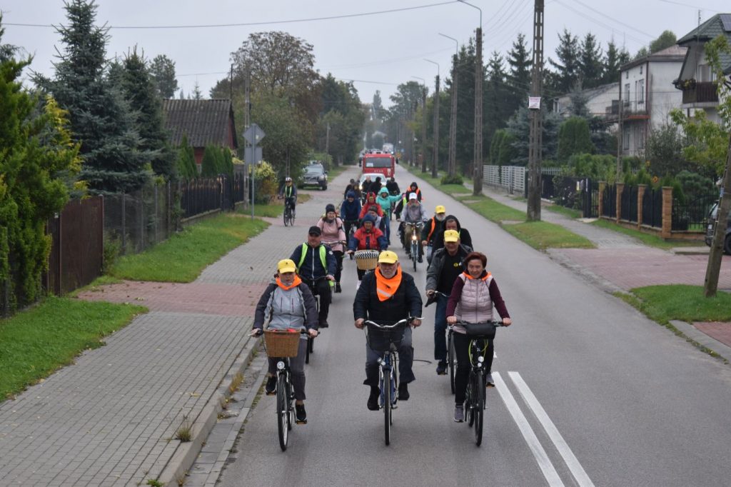 Ucszstnicy rajdu rowerowego jadący przez ulice gminy oraz podczas poczęstunku na mecie.