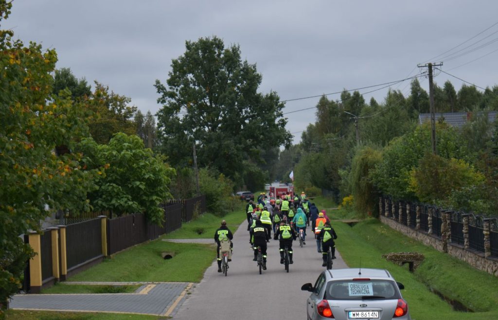 Ucszstnicy rajdu rowerowego jadący przez ulice gminy oraz podczas poczęstunku na mecie.