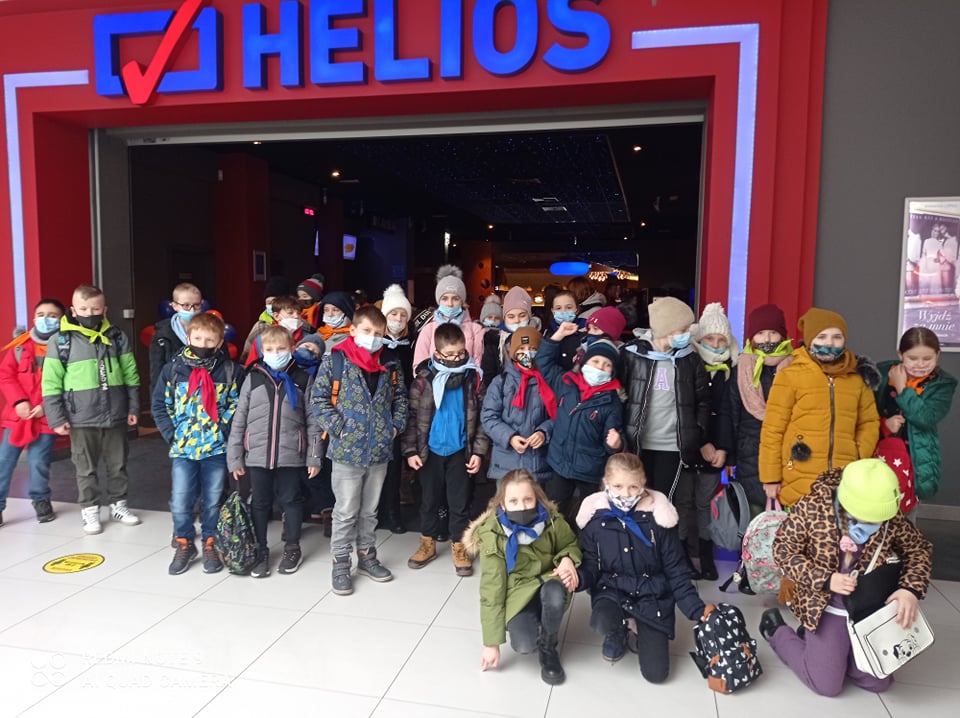 Dzieci wychodzące z kina, za nimi na czerwonym tle niebieski napis HELIOS