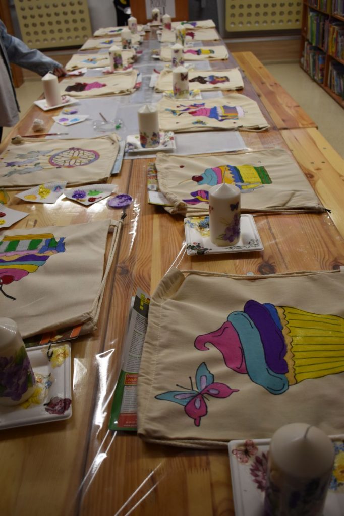 Worki które pomalowały dzieci na kolorowo i świece leżą na drewnianym stole