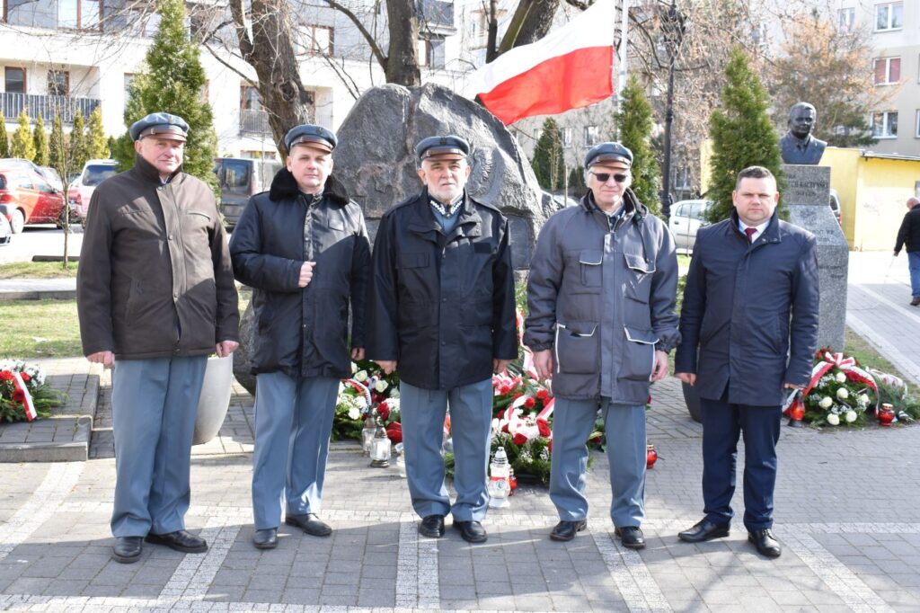Pięciu mężczyzn przed pomnikiem