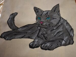 Na płóciennej torbie namalowany leżący szary kot z szafirowymi oczami i różowym nosem.