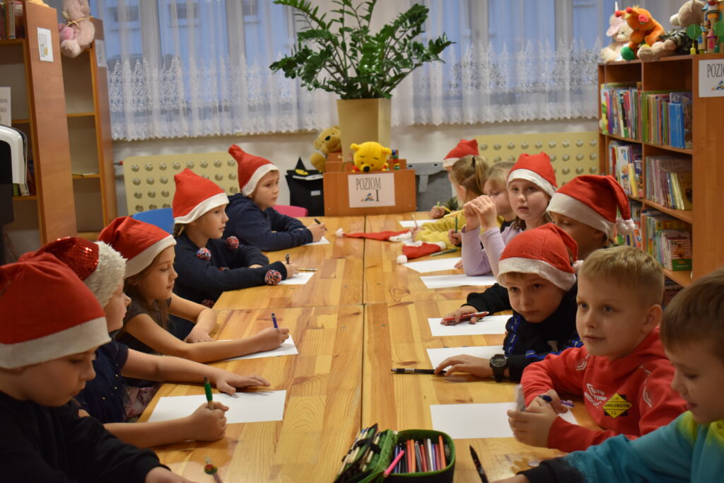 Dzieci siedzące przy drewnianym stole w czerwonych czapkach
