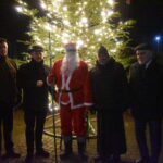 Pięciu mężczyzn stojących obok siebie. W tle drzewko świąteczne.