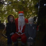 Święty Mikołaj na alejce w parku. W tle widoczny kościół.