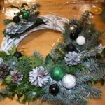 431 Wianek w kolorystyce zimowej z szyszkami i gałązkami oprószonymi śniegiem, bombki srebrne, białe i zielone.