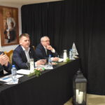 107 Trzech mężczyzn siedzi przy stole który jest przykryty czarnym suknem