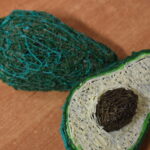 W bibliotece przy stole dzieci przesypują ryż do torebek foliowych. W tle regały z kolorowymi książkami.