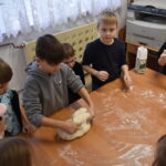 Dzieci jadą autokarem, siedzą na granatowych fotelach, które mają jasno niebieskie zagłówki.