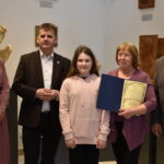 $ osoby dorosłe oraz kilkunastoletnia dziewczynka. Kobieta trzyma dyplom.