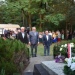 kwiaty biało czerwone grób zielona trwawa ludzie