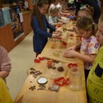 Dzieci w Bibliotece na drewnianym stole zabierają się do pieczenia pierników. W tle regały z książkami