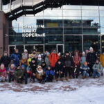 80 Na tle szklanego budynku z napisem Centrum Nauki Kopernik grupa dzieci ubrana w ciepłe kurtki na chodniku przed nimi leży śnieg