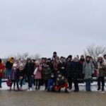 139 Grupa dzieci stoi a dwóch chłopców kuca. W tle zimowy krajobraz Warszawy