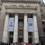 169 Grupka dzieci stoi na schodach na których leży śnieg, w tle budynek Pałacu Kultury i Nauki w Warszawie