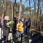 DSC_0292 Na zdjęciu jest grupa osób stojących przed ogrodzeniem. Wyglądają na skoncentrowanych, zwracając swoją uwagę ku temu, co kryje się za płotem.