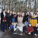 DSC_0473 Naruszone jest grupa osób pozujących do zdjęcia przed grobem. Wyrażają pamięć i pamięć o zmarłym, utrwalając dziesięć momentów na fotografii.