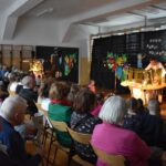 Na widocznej grupie ludzi występuję. Wszyscy są skupieni zainteresowania i tym, co dzieje się na scenie.