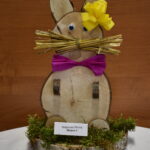 Na panelu jest wtyczka, która jest zainstalowana w systemie PCB, a także podłączony do żółtego, papierowego kwiatu i dużej części. Dekoracja jest prezentowaną na drewnianym podkładzie, przy której znajdują się etykiety.