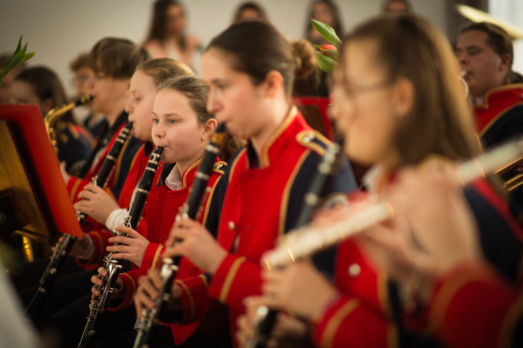 Na zdjęciu jest grupa ubrana w odpowiednie, czerwone mundurki, które grają na flecie. Powstał z nich, który składa się na twoją partię, tworzącą harmonijną melodię.