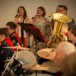 Na zdjęciu jest grupa osób tworząca zespół muzyczny. Każdy z członków trzyma swój instrument, natychmiast do rozpoczęcia występu.