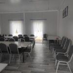 Na obrazku widocznym pustą klasę z rzędami stolików i krzeseł, białe zasłony na oknach oraz szare podłogi. Po prawej stronie można umieścić dwie ramki zamocowane na ścianie.