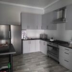 Na obrazku głównym, którego kolorem jest szarość mebli. Kuchnia jest wyposażona w sprzęty ze stali nierdzewnej i mam drewniane podłogi.