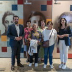 DSC_4386_11 Na obrazku znajduje się grupa sześciu osób, w tym trzech mężczyzn i trzy kobiety, które uwalniają przed wystawą zawierającą portrety historyczne. Osoby te są ubrane zarówno na co dzień, jak i formalnie, pozują do zdjęć.