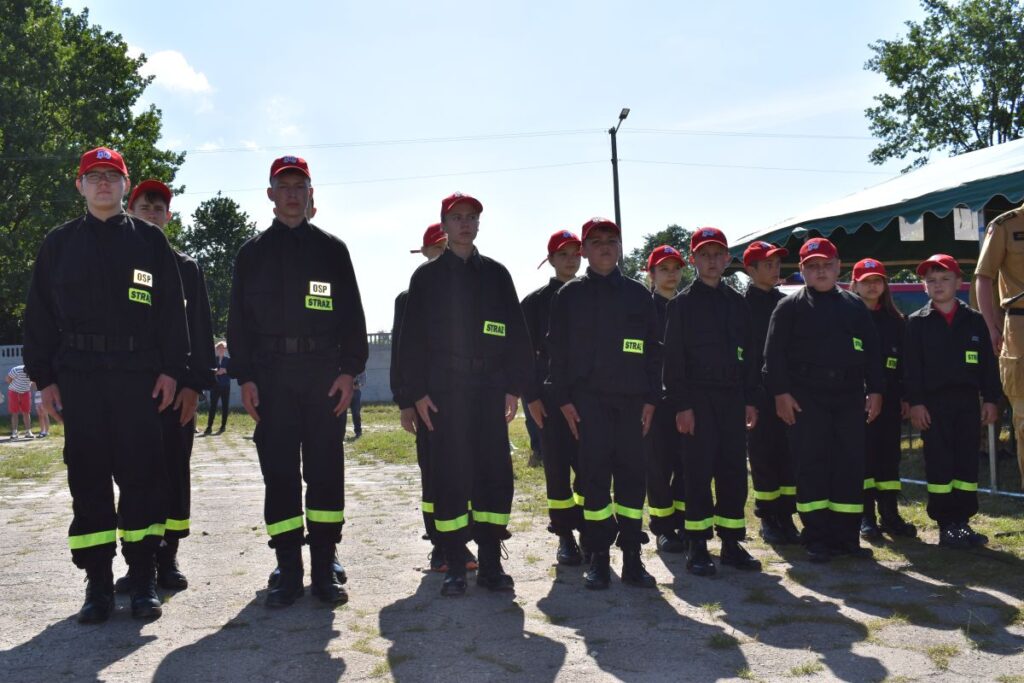 Na obrazku widoczne grupy osób, które mają na sobie jednakowe czarne mundury z odblaskowymi żółtymi pasami i czerwonymi czapkami. Stoją jeden w zwartym zagrożeniu na rozprzestrzenianie się powietrza, które może nastąpić w wyniku działania z publicznej lub społecznością.