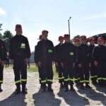 Na obrazku widoczne grupy osób, które mają na sobie jednakowe czarne mundury z odblaskowymi żółtymi pasami i czerwonymi czapkami. Stoją jeden w zwartym zagrożeniu na rozprzestrzenianie się powietrza, które może nastąpić w wyniku działania z publicznej lub społecznością.