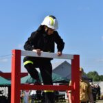 Na obrazku widocznym ubranego na czarno, który wspina się przez czerwone światło podczas działania na zewnątrz powietrza. Obok niego stoi inna osoba w brązowym uniformie, a jego działanie.