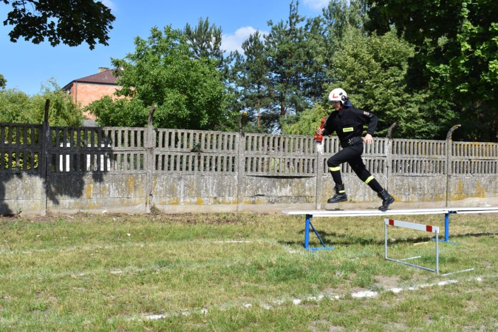 Na obrazku żołnierza i kasku biegnie po wyjściu z ćwiczeń szkoleniowych na zewnątrz. W tle widać drzewo i ogrodzenie.