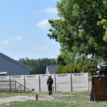 Na obrazie widocznym na szkoleniu; jeden drewniany wspina się po drewnianej ścianie, inny idzie w jej drodze, a trzeci raz w przebiegu ćwiczeń. Scena ma miejsce na świeżym powietrzu w pobliżu budynku i drzewa.