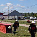 Na obrazku dzieci ubranych w strażackie mundury uczestniczące w terenie torze oddzielne. Jedno dziecko czołgające się przez czerwony tunel, podczas gdy dwaj inni biegają w pobliżu.