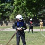 Na obrazach, które otrzymali podczas szkoleń, ubranych w stroje i kaski. Trzymają węże strażackie, ćwicząc na tle drewna i drewnianego ogrodzenia.