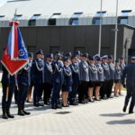 Na zewnątrz znajduje się grupa umundurowanych policjantów stojących w zagrożeniu na świeżym powietrzu, a dwa dostępne są z prawej strony. Po lewej stronie jeden z poliestrów trzyma flagę.