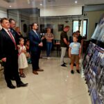 20240801_170817 Grupa ludzi, w tym strażacy i dzieci, oglądają wystawę tradycyjnych informacji i fotografii na stojących panelach w eleganckim pomieszczeniu. Wszyscy mogą być zainteresowani prezentowanymi materiałami.