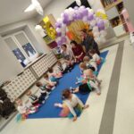 Na obrazku znajduje się grupa młodych dzieci i dorosłych siedzących na innym macierzy w pokoju wyposażonym w balonami oraz znaczeniem z cyfrą 6. Scena amerykańska, która może być używana na licencji rodzinnej dla sześcioletnich dzieci.