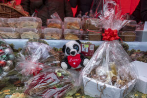 Na obrazku znajduje się kosze upominkowe w celofanie i ozdobione świątecznymi wstążkami. Obok jest pluszowa panda trzymająca serce z napisem „Miłość”.