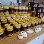 476558839_649842764057915_5222169792207629131_n Na miejscu znajduje się kilka opakowań miodu o różnych rozmiarach i etykietach, z przodu, są małe, białe pojemniki. Delikatna substancja kolorowa i zachęcająca do prezentowania produktów pszczelarskich.