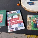 Na stołeczne trzy książki dotyczące polskiej tradycji i kultury, w tym jednej encyklopedii. Książki są umieszczone obok siebie i stanowią źródło wiedzy o polskim dziedzictwie.