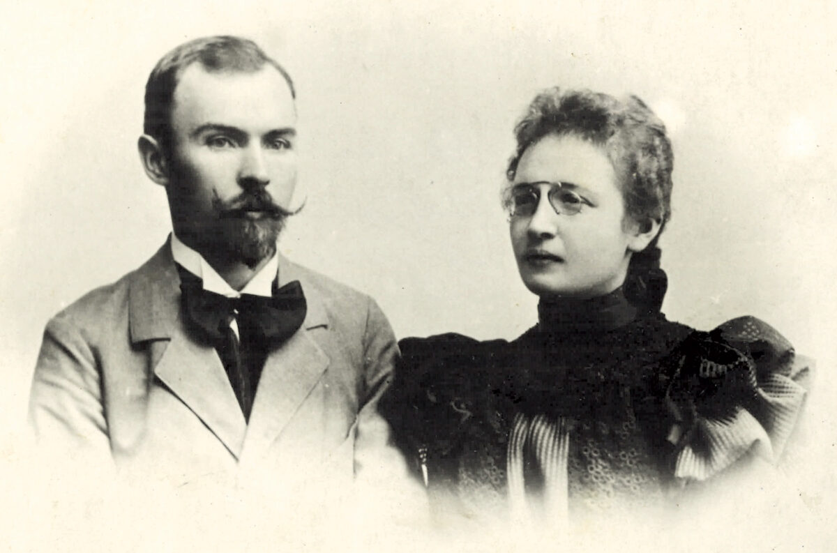 Czarno-białe zdjęcie portretowe przedstawia mężczyznę w garniturze i kobietę w okularach. Mają poważne wyrazy twarzy. Tło jasne, jednolite.