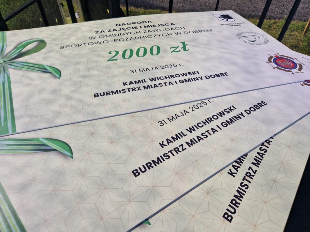 Nagroda za zawody, czek na 2000 zł, biały z zieloną kokardą. Widoczne logo straży pożarnej i herb. Daty i nazwiska na czeku.