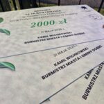 Nagroda za zawody, czek na 2000 zł, biały z zieloną kokardą. Widoczne logo straży pożarnej i herb. Daty i nazwiska na czeku.