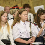 Mężczyzna pokazuje dzieciom ekranie układ słoneczny, pięciu chłopców mu się przygląda. W tle regały z książkami i czarna kotara na której pokazane jest zaćmienie słońca.