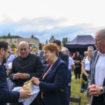 Uśmiechnięte dzieci siedzą przy stole i trzymają breloczki, za nimi regały z książkami