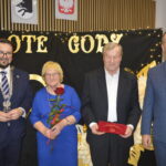 Cztery osoby pozują przed czarnym tłem z napisem Złote Gody. Kobieta w niebieskiej sukni trzyma czerwoną różę. Mężczyźni mają na sobie ciemne garnitury.