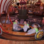 619677056_2255053428352316_1098095600859199917_n Trzy młode osoby siedzą na wikingowskiej łodzi w wesołym miasteczku. Łódź jest ozdobiona tarczami i ma czerwono-białe żagle. W tle widać inne łodzie i drewniane konstrukcje na tle kolorowych świateł.