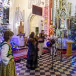 Grupa muzyków w strojach ludowych gra w kościele, ozdobionym kolorowymi światełkami i choinkami. Wnętrze utrzymane jest w jasnych barwach ze złotymi zdobieniami. Na podłodze czarno-biała szachownica.