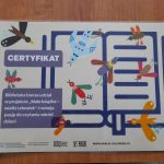 Certyfikat z kolorowymi ptakami na beżowym tle. Podkreśla udział biblioteki w projekcie czytelniczym dla dzieci. Tekst w fioletowych prostokątach.